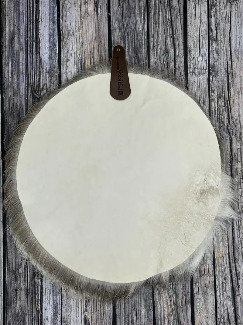 A white round reindeer hide seat cover with a leather strap